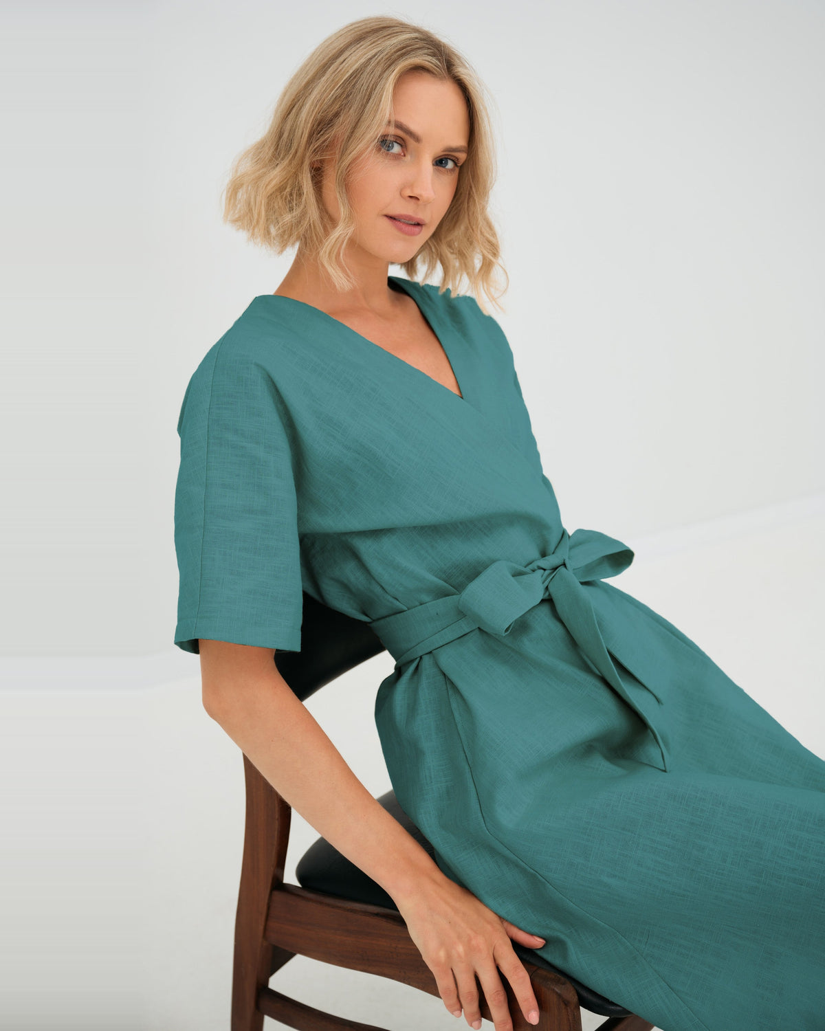 LeMuse CHLOE linen dress in teal – seated close-up, bow detail #Color_Teal