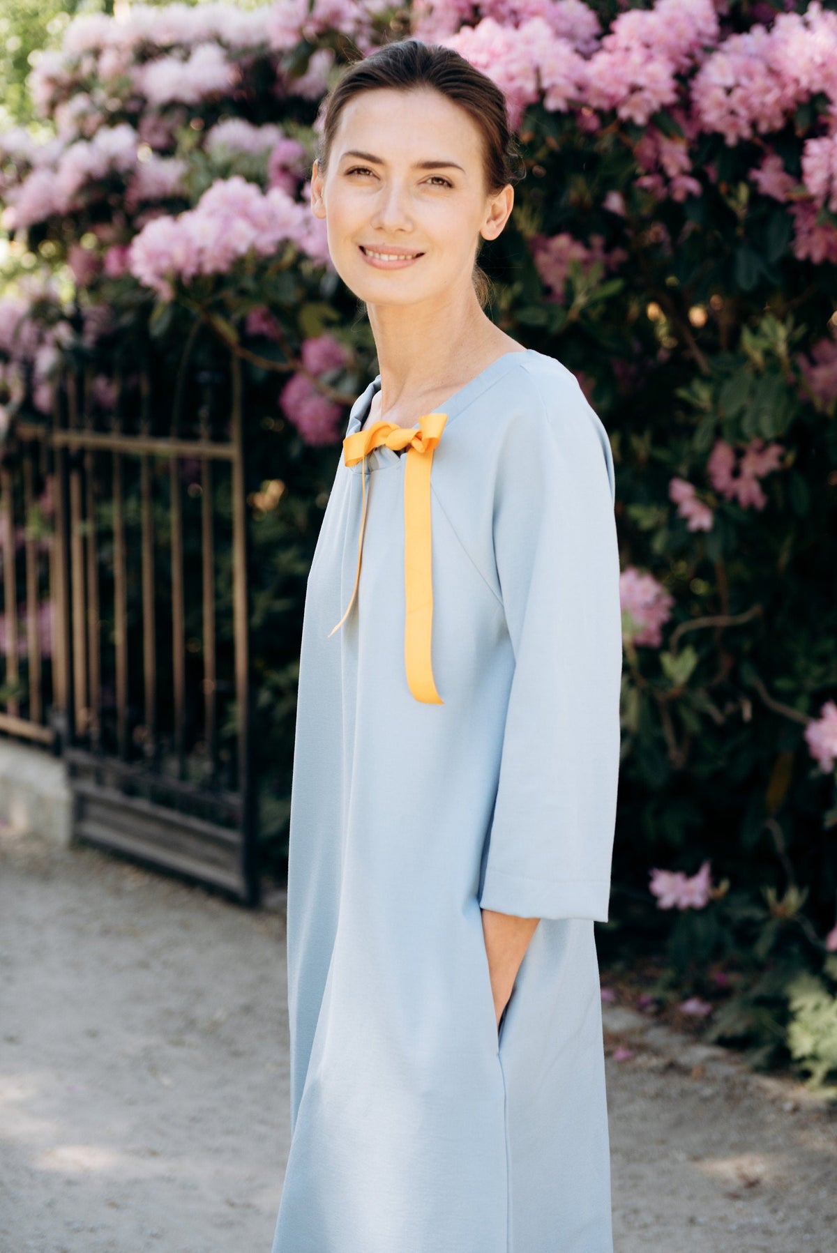 FRENCH – Italian Punto Milano Ribbon Neck A-Line Dress – sky blue dress, three-quarter view in a garden with a yellow ribbon bow #Color_Sky blue