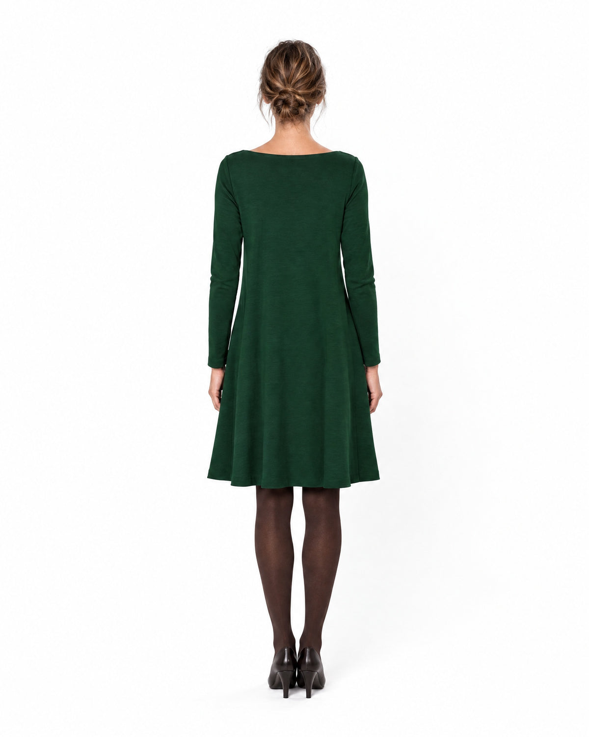 A woman modeling a dark green long-sleeve A-line dress with a boat neckline, seen from behind showing the back and A-line skirt. #Color_Green