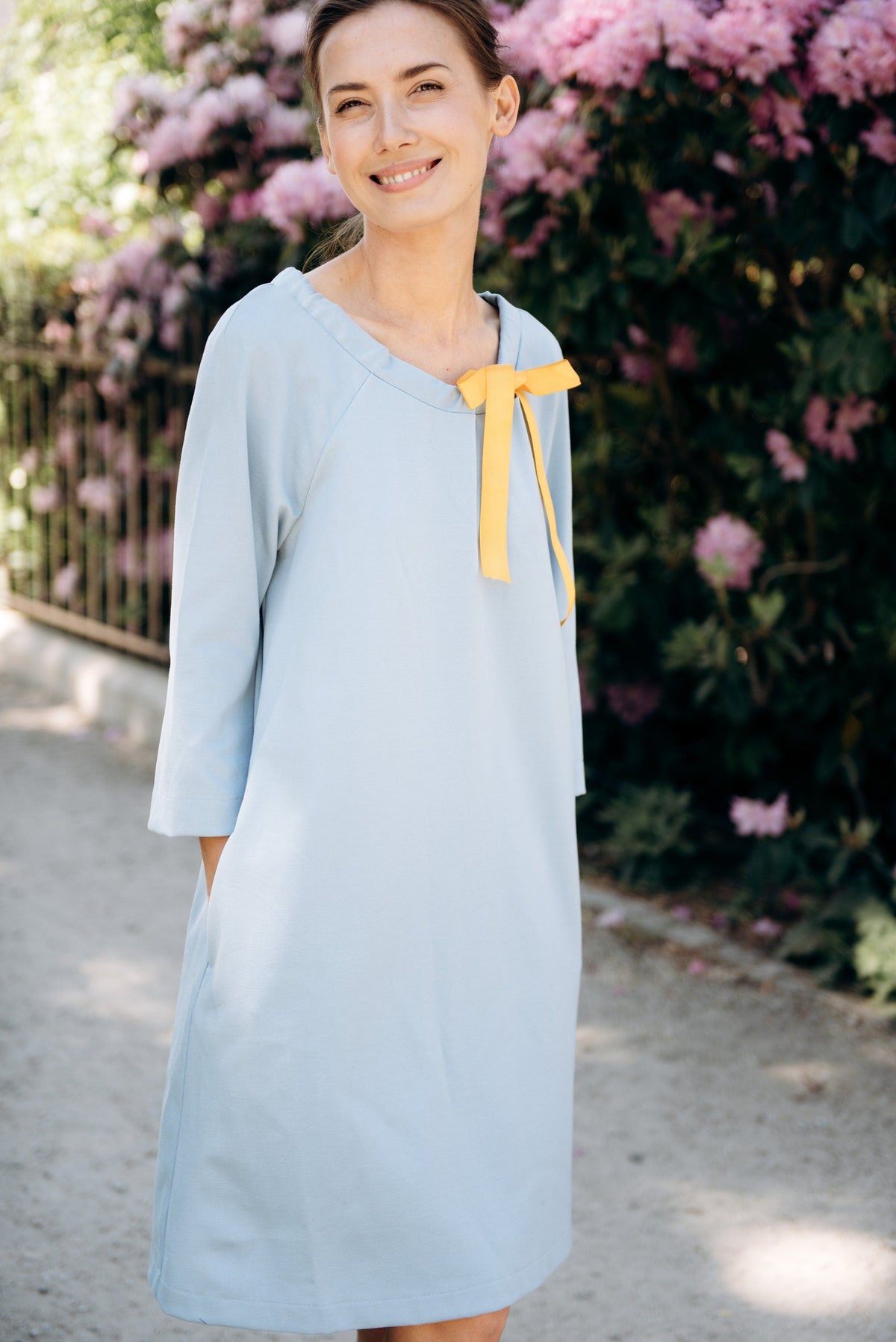 FRENCH – Italian Punto Milano Ribbon Neck A-Line Dress – sky blue dress, front view in a garden with a yellow ribbon bow #Color_Sky blue