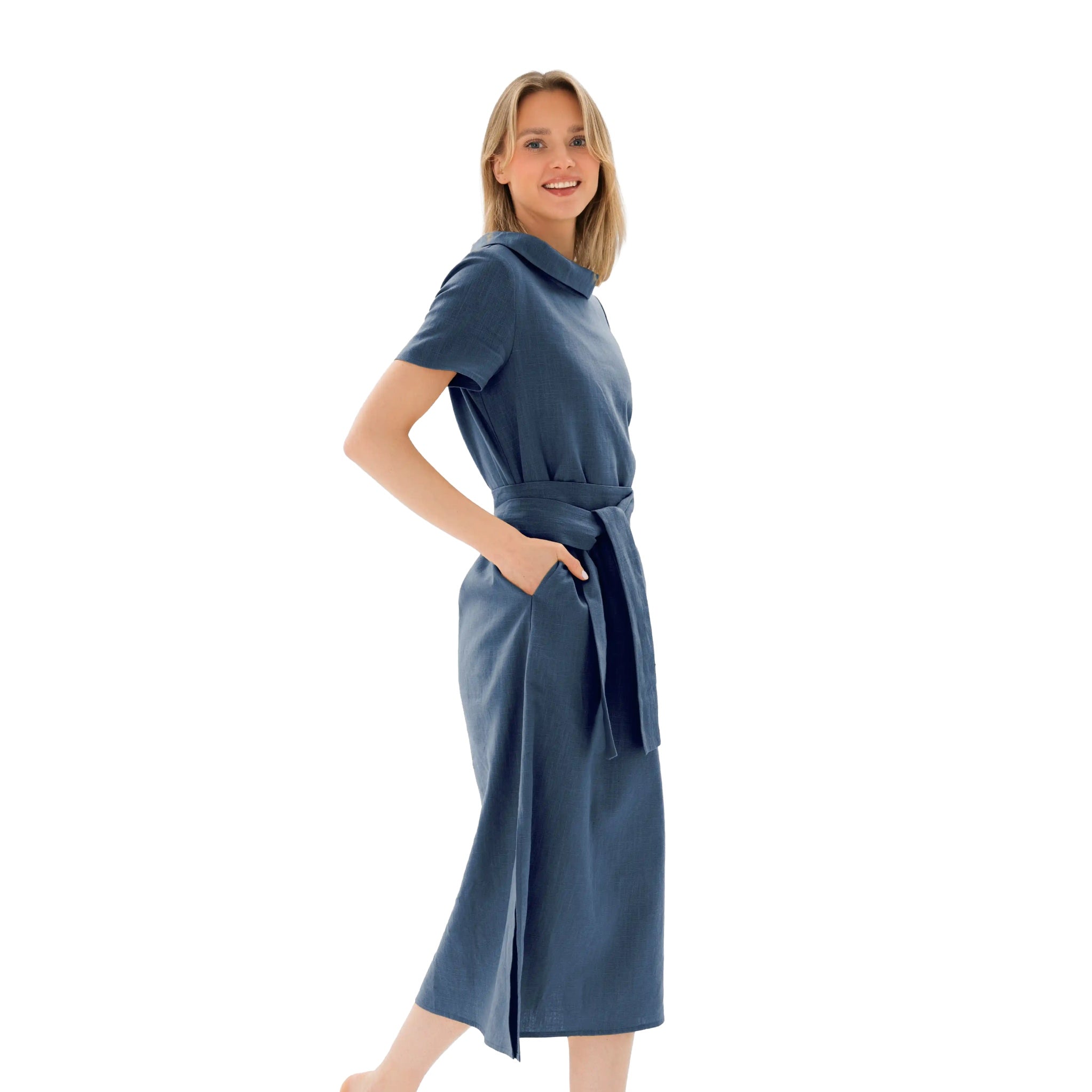 A woman modeling a slate blue midi dress with short sleeves, a high folded collar, a matching waist tie belt, and side pockets, set against a plain white background.
