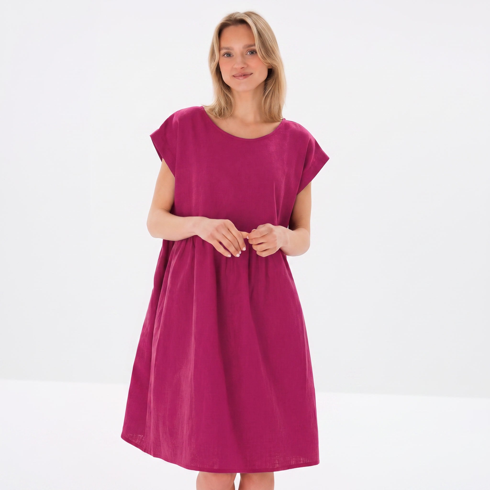 A woman modeling a short-sleeved, knee-length magenta dress against a clean white studio background.