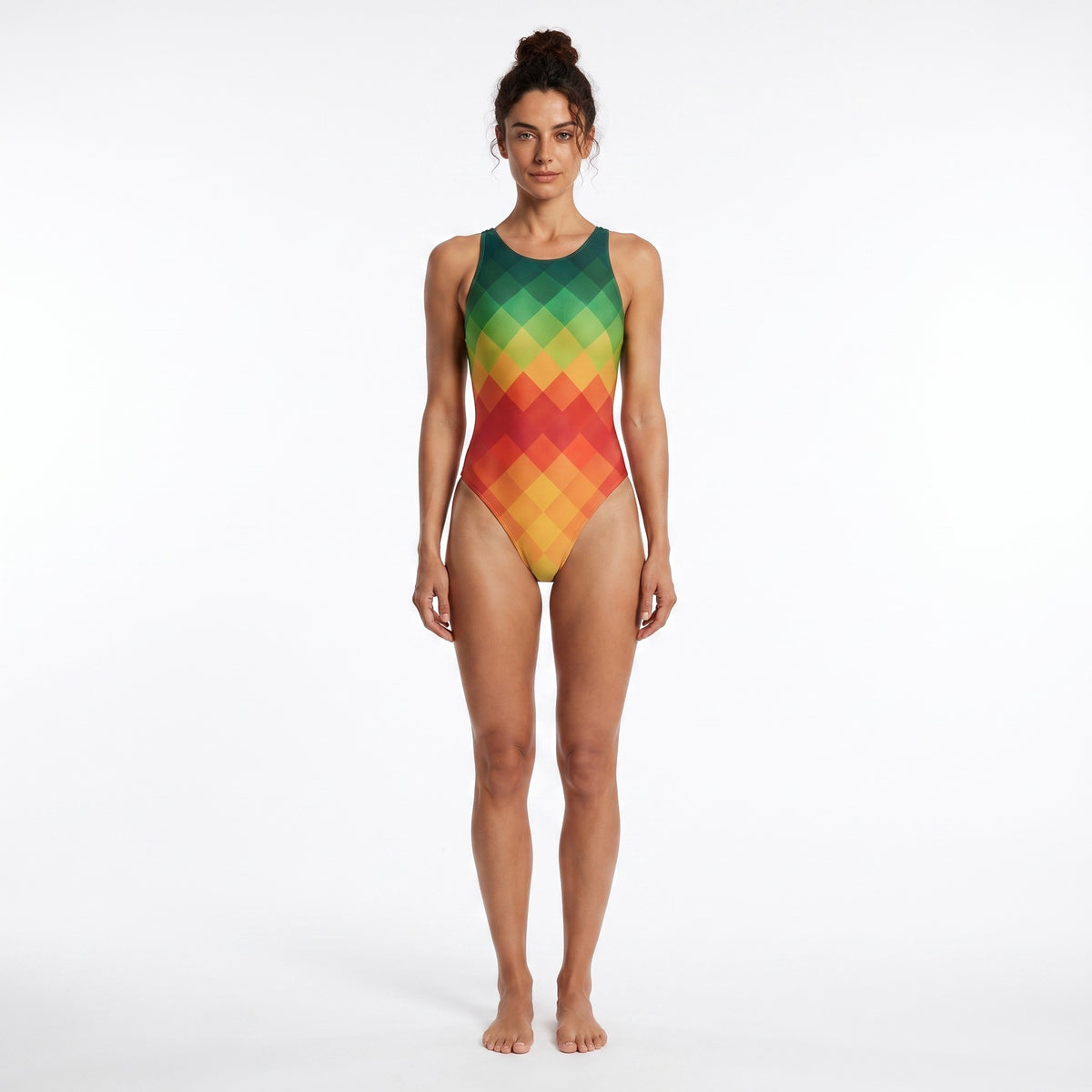 A woman modeling a sleeveless one-piece swimsuit with a geometric diamond pattern in a green-to-yellow-to-red gradient, standing against a plain white studio background.